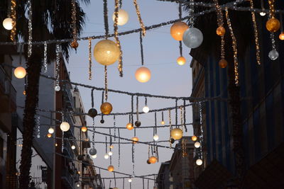 Low angle view of illuminated decorations hanging against sky at dusk