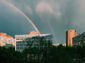 Double rainbow over buildings in city against sky