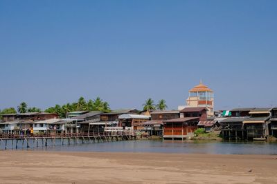 Buildings on beach against clear blue sky