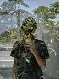 Close-up of person holding potted plant against trees