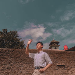 Full length of young man standing on land against sky