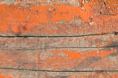 Close up shot of old orange paint texture peeling off wood plank background