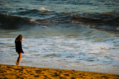 Full length of woman standing at sandy beach