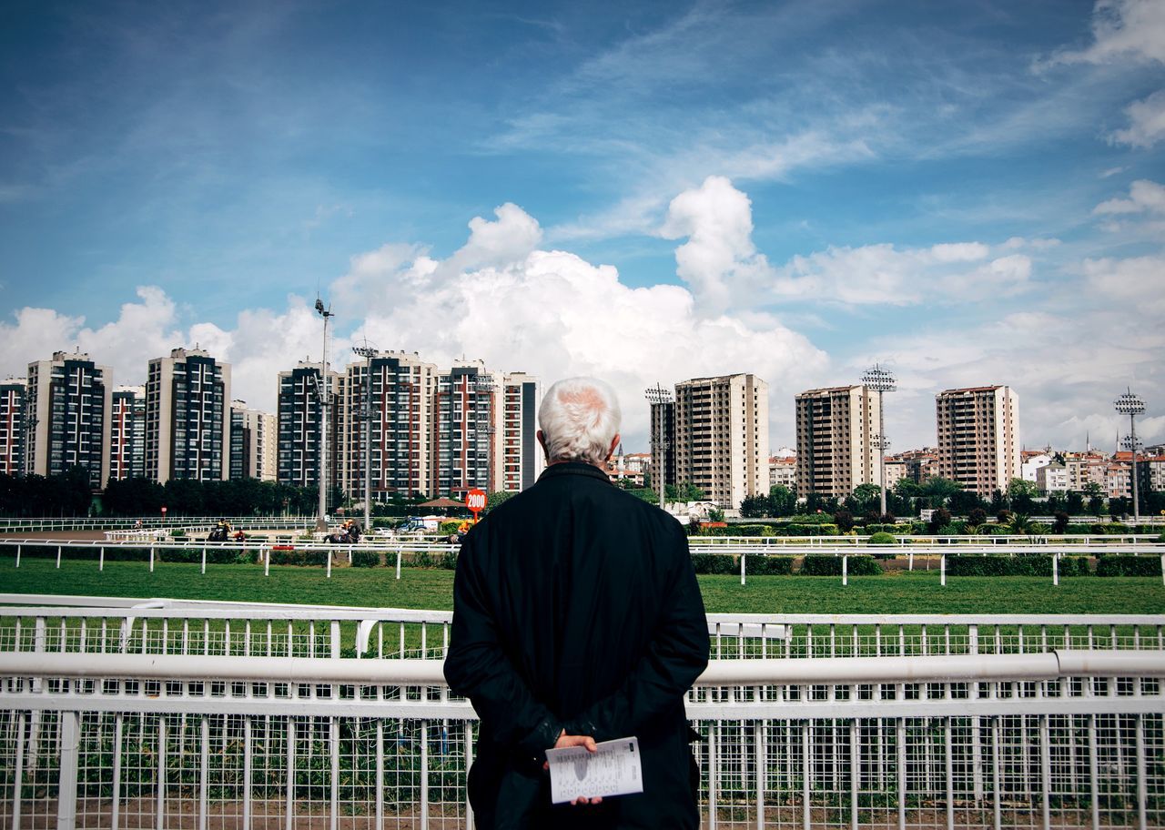 MAN STANDING AGAINST CITYSCAPE