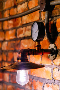 Close-up of electric lamp on brick wall