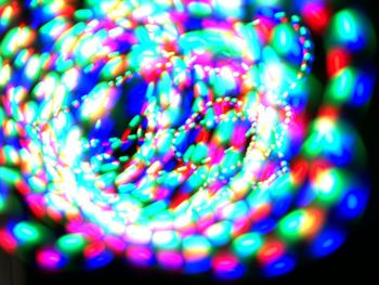 Defocused image of illuminated lights against black background