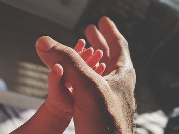 Cropped image of son holding father hand