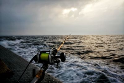 Close-up of camera on sea against sky during sunset