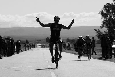 Rear view of people riding bicycle on road