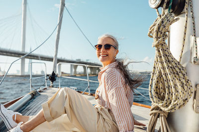 Woman with umbrella on boat in sea against sky