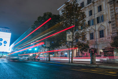 Light trails on street amidst buildings in city at night