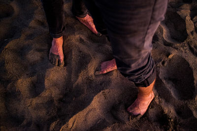 Low section of man standing on sand