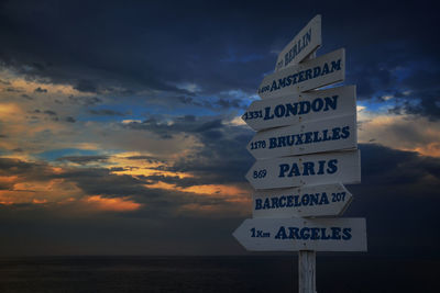 Low angle view of information sign against sky during sunset