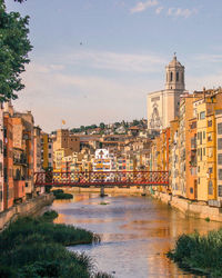 Buildings by river against sky in city