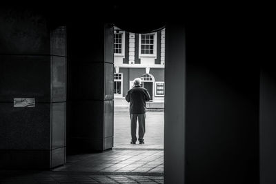 Full length rear view of man walking in corridor