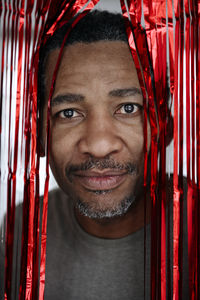 Mature man looking through red tinsel curtain