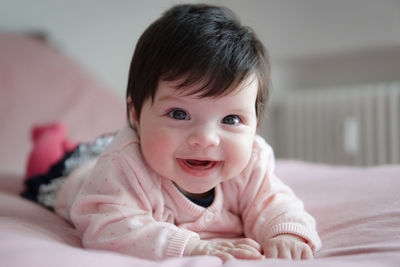 Portrait of cute happy baby girl on bed at home