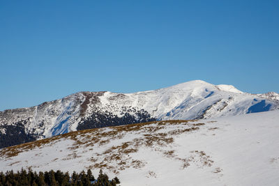 Scenic view of snowcapped mountains against clear blue sky