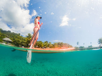 Woman with arms raised in sea against sky