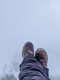 Low section of man wearing leather shoes against sky