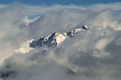 Scenic view of snow covered mountains against cloudy sky
