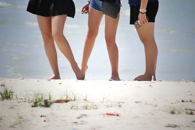 Low section of female friends standing at beach