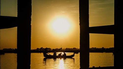 Silhouette people on river against sky during sunset