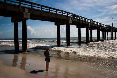 Side view of girl standing at beach against sky during sunny day