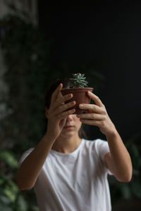 Portrait of young man holding flower pot on potted plant