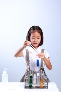 Schoolgirl performing scientific experiment against blue background
