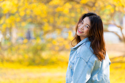 Portrait of a smiling young woman standing during autumn