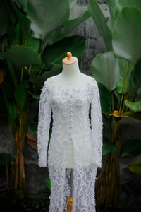 White wedding dress on a mannequin captured in an outdoor garden.