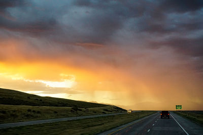 View of country road against cloudy sky