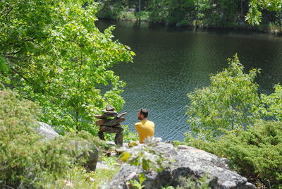 Man sitting by stack rock at lake