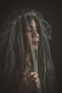 Portrait of young woman holding cigarette against black background