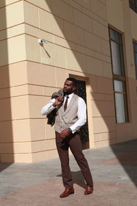 Young man looking away while standing against building