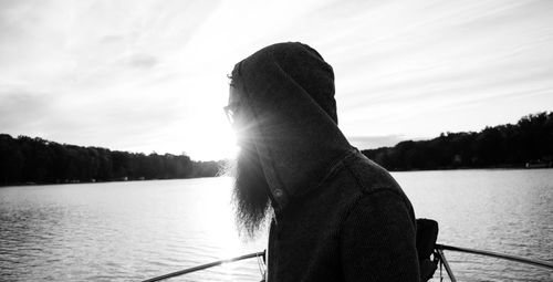 Thoughtful man sailing on boat on river against sky during sunset