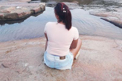 Rear view of woman sitting on rock