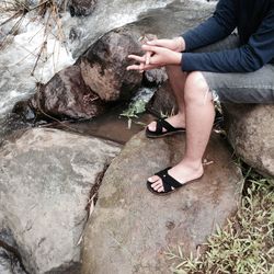 Low section of man sitting on rock