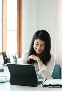 Smiling businesswoman using laptop at office