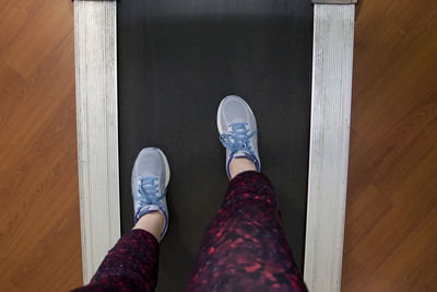 Low section of person wearing shoes on hardwood floor