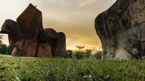 Statue on field against sky at sunset