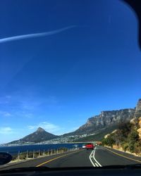 Road by mountain against blue sky