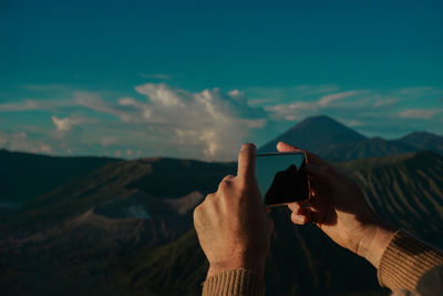 Cropped hands photographing mountains from mobile phone