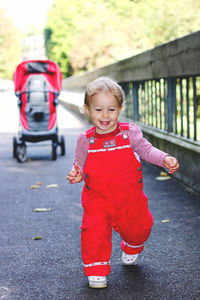 Portrait of cute smiling baby running away from stroller 