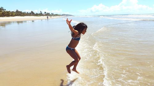 Full length of young woman standing at beach