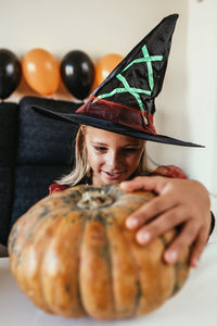 Portrait of woman holding pumpkin against wooden wall during halloween