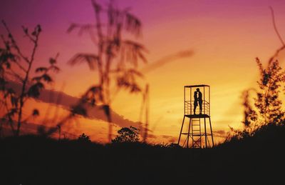 Silhouette trees on field against orange sky