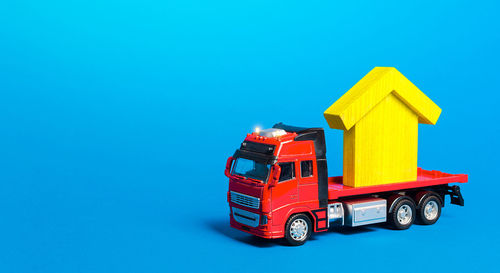 Red freight truck carrier with a yellow house figure. home moving company. 