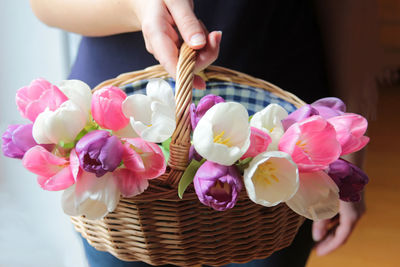 Close-up of hand holding pink flowers in basket